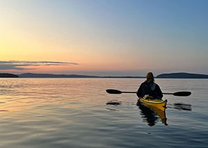 Person kayaking at sunset