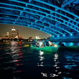 People kayaking under bridge