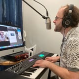 Guy Playing Piano and Singing in Front of Computer