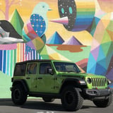 Green Jeep in front of art wall