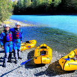 Two People Standing Next to Raft Near Water