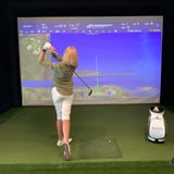 Woman playing golf with simulator