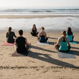 Group Sitting on Yoga Mats on Beach