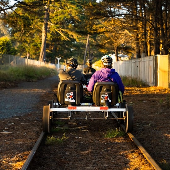 Two people riding railbikes at sunset
