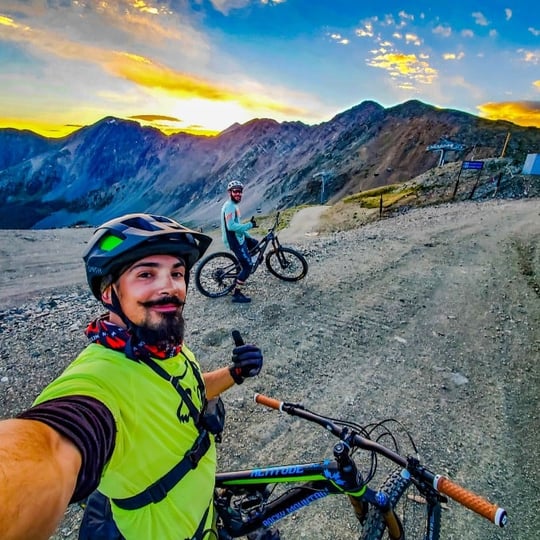 Two people mountain biking at sunset