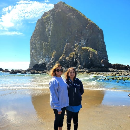 Two woman on beach with giant rock