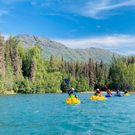 People Rafting in Water with Mountain Background