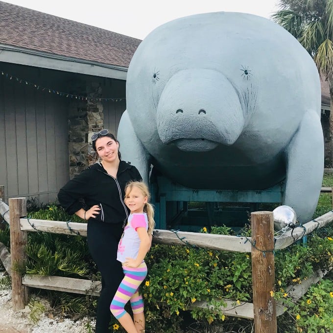 Mom and daughter in front of manatee statue