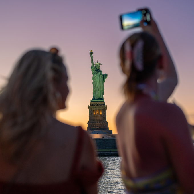 Woman taking picture of Statue of Liberty