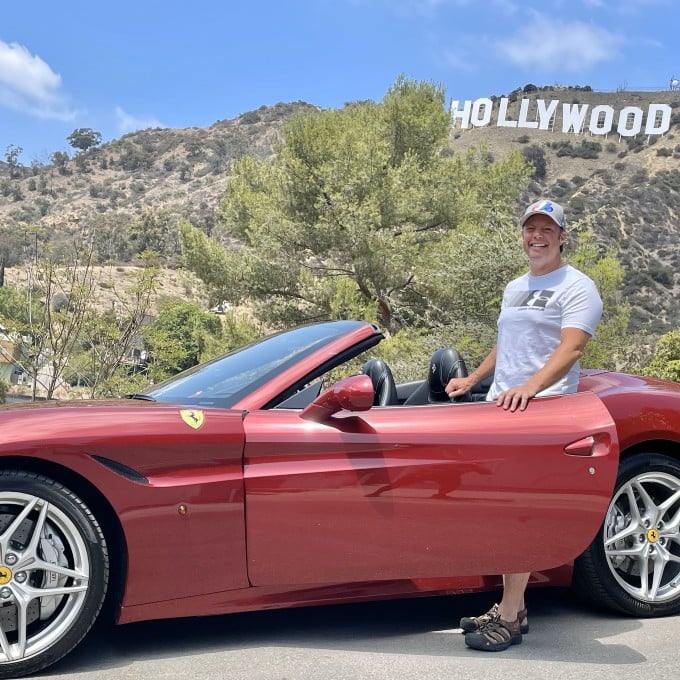 Man in front of Hollywood sign in Ferrari