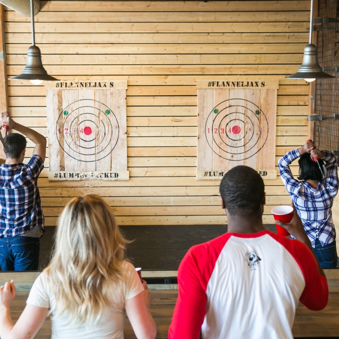Two People  Watching Others Throw Axes