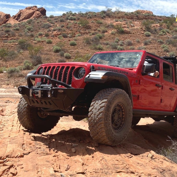 Red Jeep climbing up rock