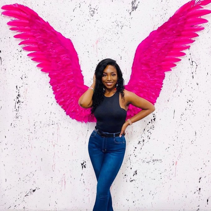 Woman Posing in Front of Pink Wings