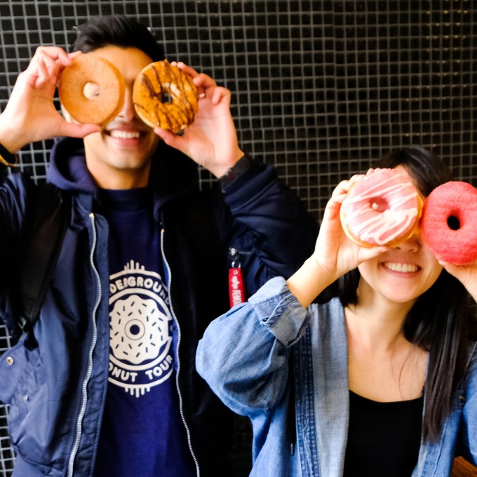 Two People Holding Donuts up to Eyes