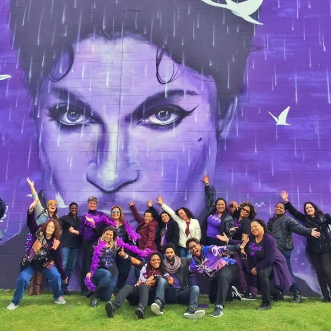 Group posing in front of Prince mural
