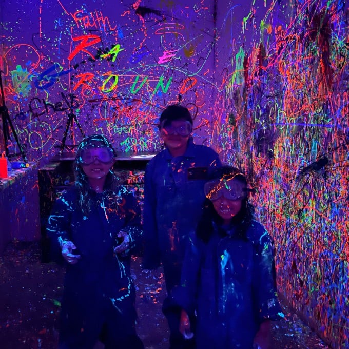 Group Posing in Dark Splatter Room with Glow in the Dark Paint