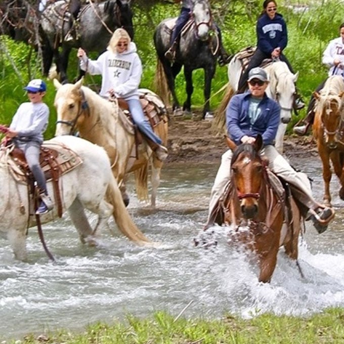 Group Riding Through Water on Horses